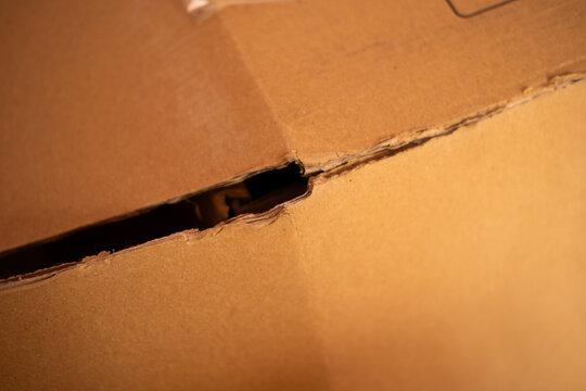 Damaged brown cardboard box opening, revealing an unexpected peek inside a delivered fragile package