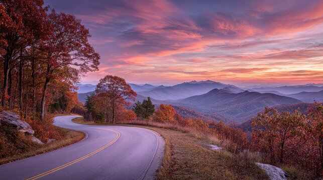 Winding road curves through colorful autumn mountains under a vibrant sunset sky. Scenic travel background.