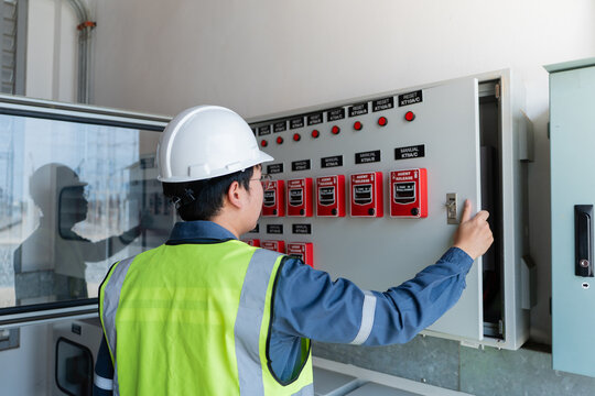 Fire protection system control panel is opened by a technician wearing a hard hat, showing an indicator light and glass window.