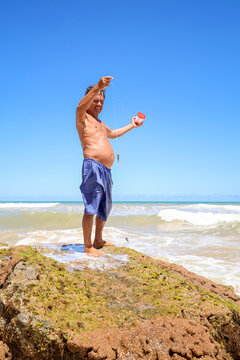 Man Fishing From a Rock by the Sea