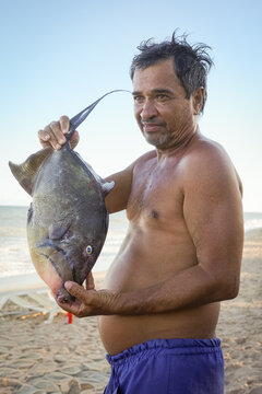 Fisherman proudly displaying his triggerfish on the beach