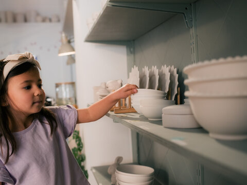 Child picking bowl from shelf at ceramic store