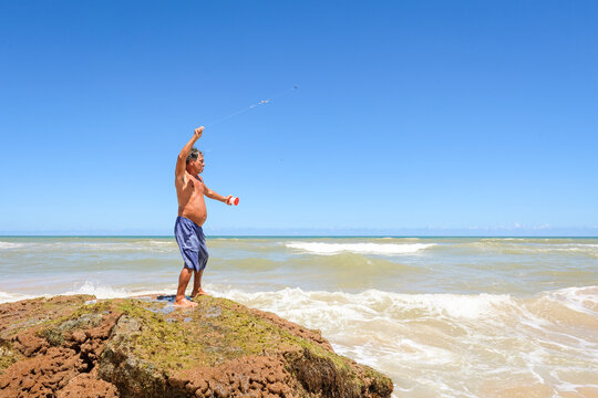 Man Stands on Rock and Fishes by the Sea
