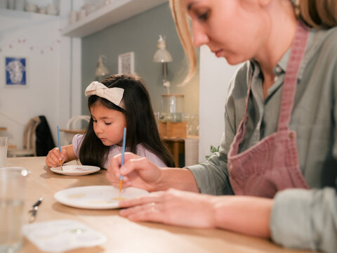 Mother and Daughter Paint Together in a Cozy Studio During the Day