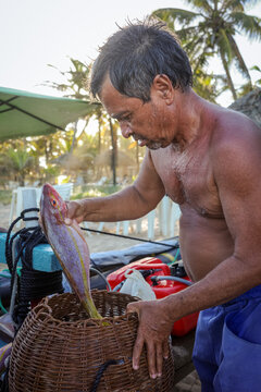Fisherman placing fresh catch into woven basket