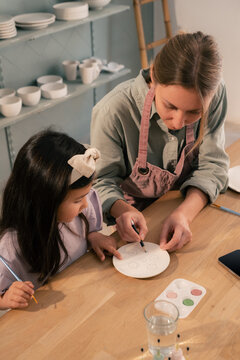 Mom helping to daughter to decorate plate