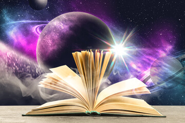 Fototapeta premium Open book on table against space with planets. Wonderful world of fantasy