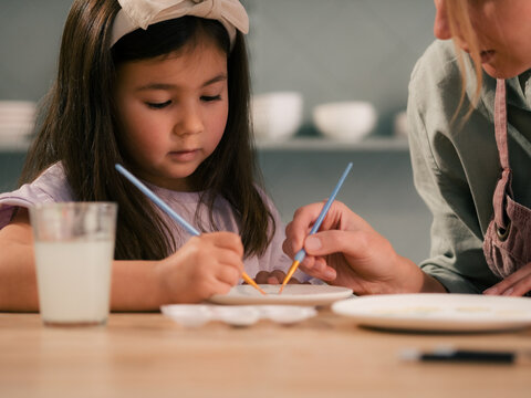 Mom helping to her daughter with painting