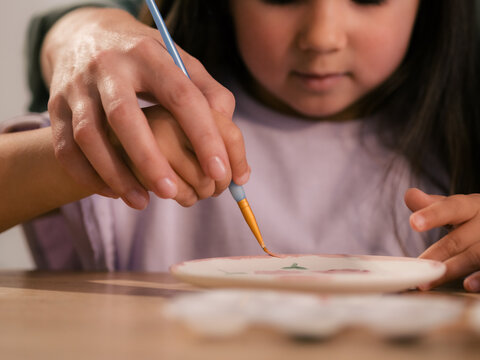 Adult helping child to paint