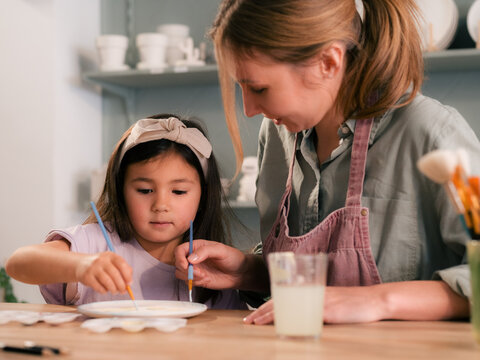 Mother and daughter talking and painting