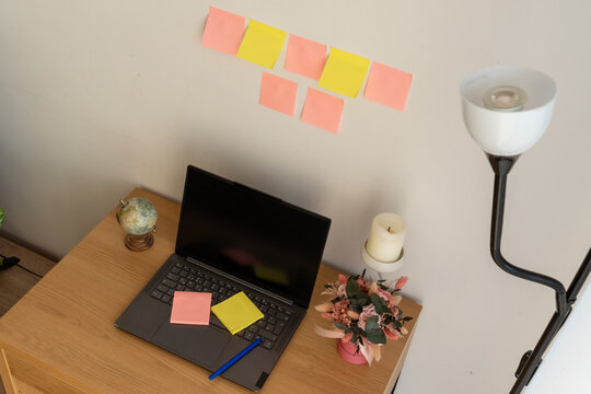 High angle view of laptop and colorful sticky notes arranged for brainstorming in cozy home office. Concept of business strategy, workflow organization, deadlines and productivity.