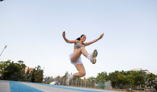 Young woman performing long jump on outdoor track