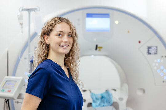 Female doctor posing near an MRI or CT scanner in a hospital. Concept medical diagnostics, healthcare professional and imaging technology.
