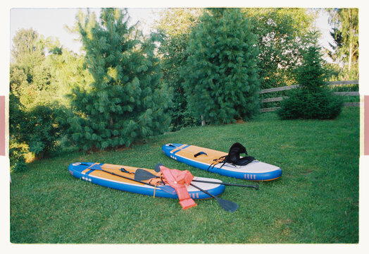 Two inflatable SUP boards resting on a summer lawn
