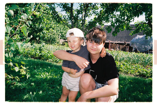 Teenage boy hugging a toddler in a sunny home garden