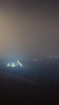 Vertical video - Timelapse of a rural town blanketed by the fog at night