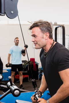 Muscular man performing cable triceps pushdown