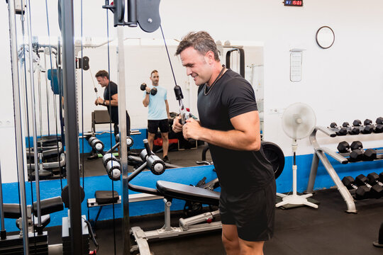 Athletic man training triceps on a cable machine