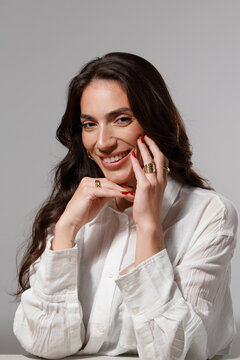Woman Smiles While Posing Indoors With Hands on Her Chin