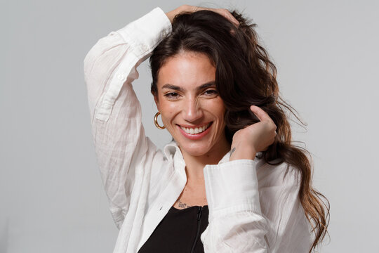 Person With Long Hair Smiling While Touching Their Hair Indoors