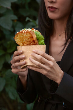 Woman holding sandwich in paper wrapper during business lunch