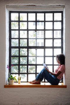 Woman Reading Beside Large Grid Window