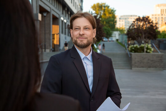 Business professional with documents meeting colleague outdoors