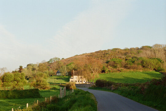 A winding country road past a house in a valley