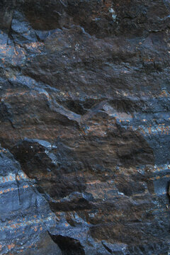 Rugged dark stone surface with bluish grey tones and brown mineral streaks