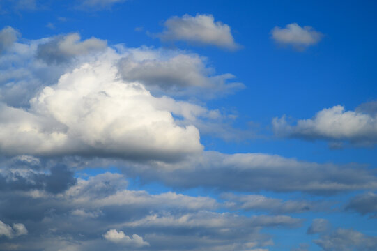 White fluffy cumulus clouds floating in bright blue atmospheric sky