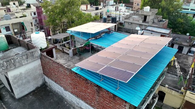 Drone Orbit shot above residential rooftop photovoltaic solar panels in a sunny Indian town, emphasizing sustainable decentralized electricity.