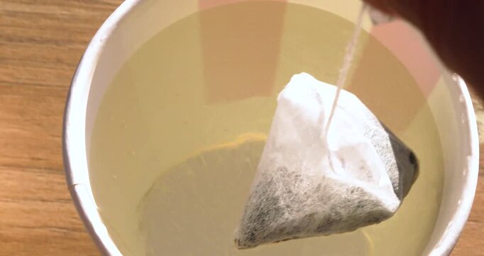 Steeping a mango-flavored green tea bag in a glass of boiling water; good morning.