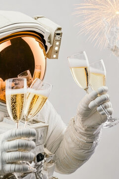 Astronaut holds glass of champagne in space suit, possibly celebrating achievement or milestone vertical frame