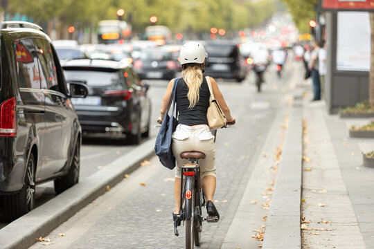 Woman riding a bicycle on Champs-&Eacute;lys&eacute;es in Paris amid urban traffic, representing sustainable transportation and modern city mobility