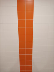 White ceramic tile wall with vertical orange tile stripe