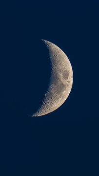 Beautiful vertical view of a sharp crescent moon in a dark blue night sky background
