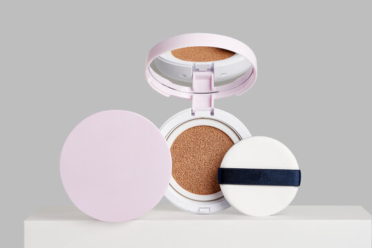 An open compact cushion foundation with beige makeup sponge