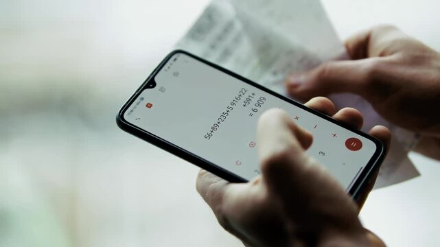 Person Holding Paper Receipt Calculation Expenses Using Calculator App On Smartphone Screen. Household Accounting