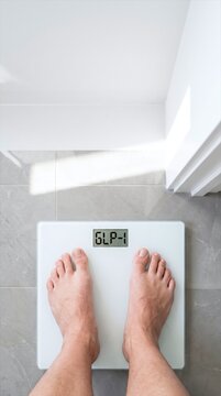 GLP-1 weight loss journey shown by bare feet standing on a digital bathroom scale.
