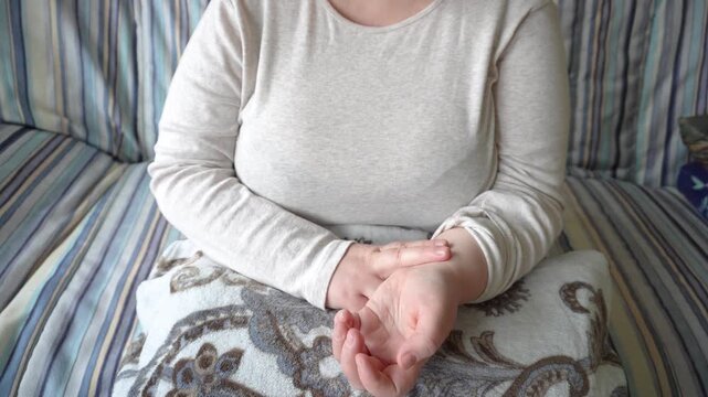 A woman measures the pulse on her arm. A woman measures her pulse on her wrist, monitoring her heart rate, a concept of health and self-control.