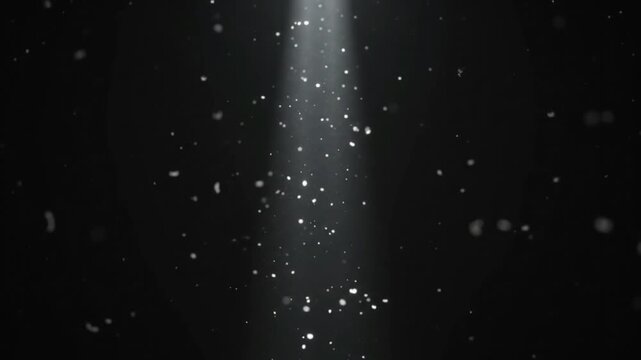Spotlight shining down on floating dust particles and glowing sparkles in a dark room