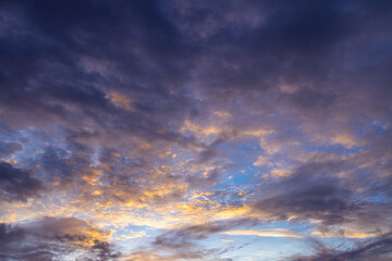 Fototapeta premium Dramatic Twilight Sky with Dark Storm Clouds and Golden Sunset Glow,A dramatic twilight sky filled with dark purple storm clouds and golden sunlight glowing near the horizon. Ideal for natural