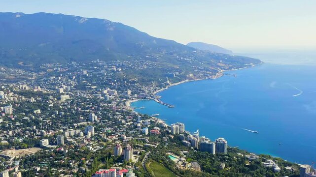 Yalta, Crimea. Panorama of the city in sunny weather. Embankment and port. Drone footage