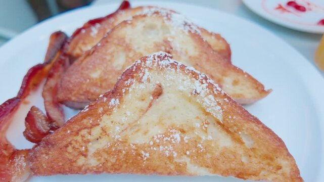 Golden Brown French Toast Slices with Powdered Sugar and Crispy Bacon