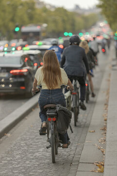 Cyclists riding along Champs-&Eacute;lys&eacute;es in Paris at dusk in late summer amid busy urban traffic