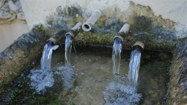 Fresh Spring Water Flowing From Old Pipes Into Stone Basin