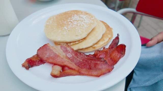 Stack of Fluffy Pancakes with Powdered Sugar and Strips of Crispy Bacon