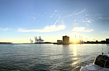 Sunrise over industrial harbor with cranes and tanks © Novanture