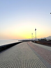 Fototapeta premium Seaside promenade at sunset with cobblestone path and sea