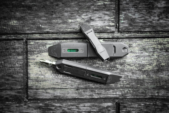 Titanium EDC pry bar multi tools flat lay on dark rustic weathered wood surface